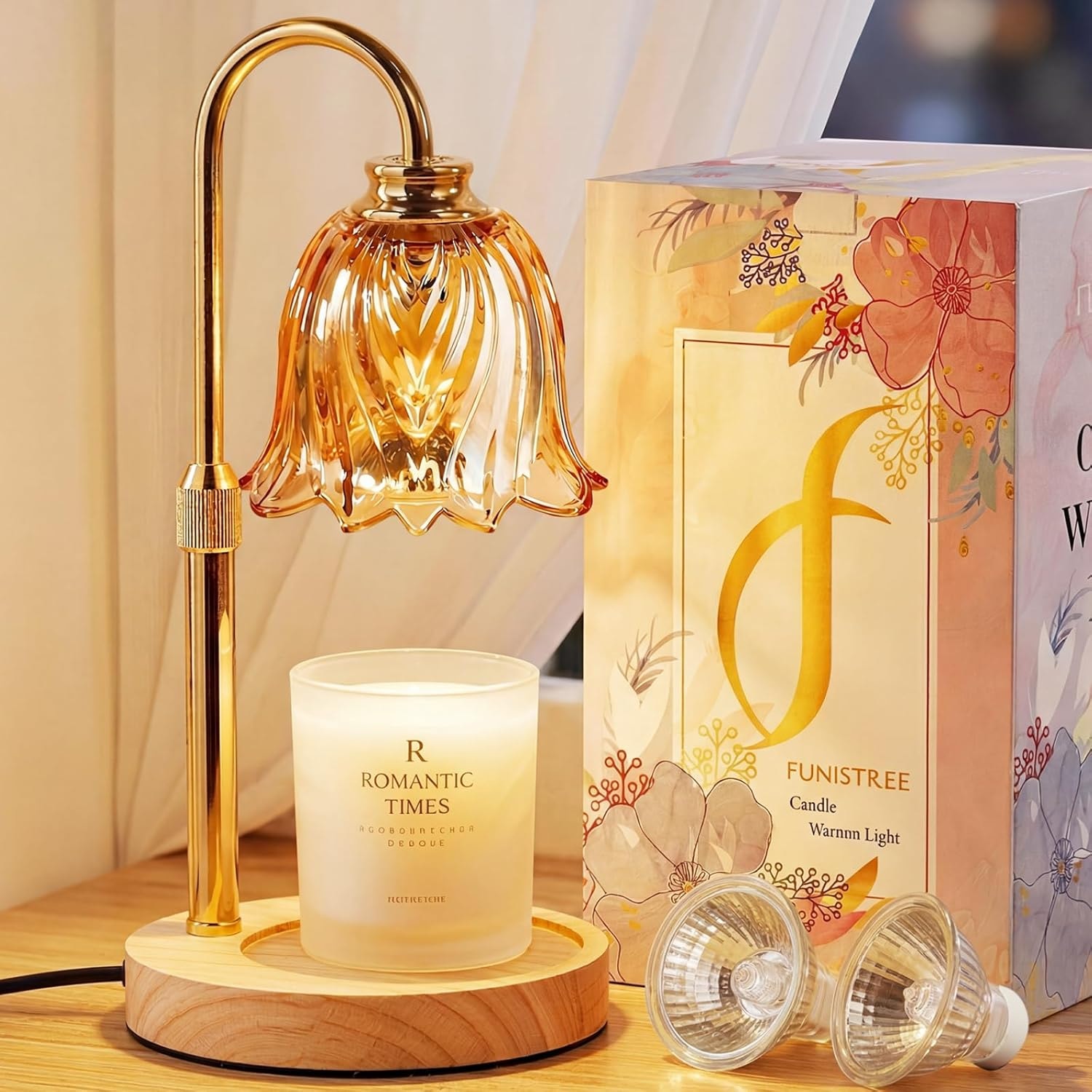 Amber petal-cut candle warmer lamp lit over a white jar candle beside a floral gift box and two spare bulbs